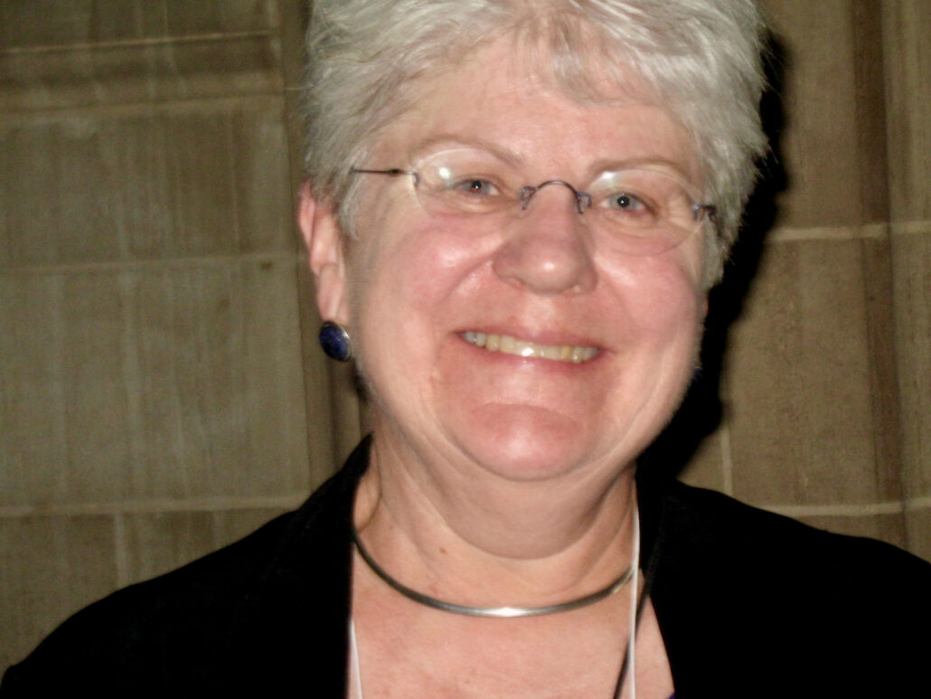 Photo of Diann L Neu. She has short white hair, glasses, and is smiling.