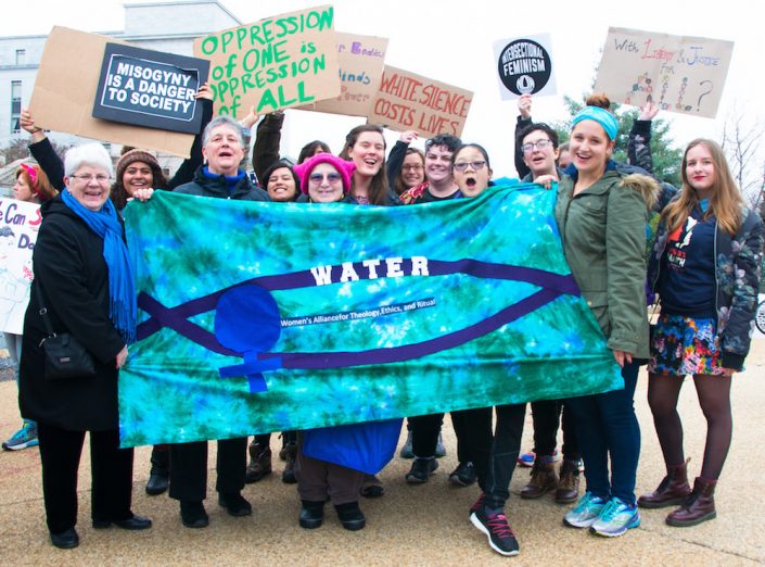 WATER staff and friends, gathered behind a blue WATER banner, at the 2018 Women's March